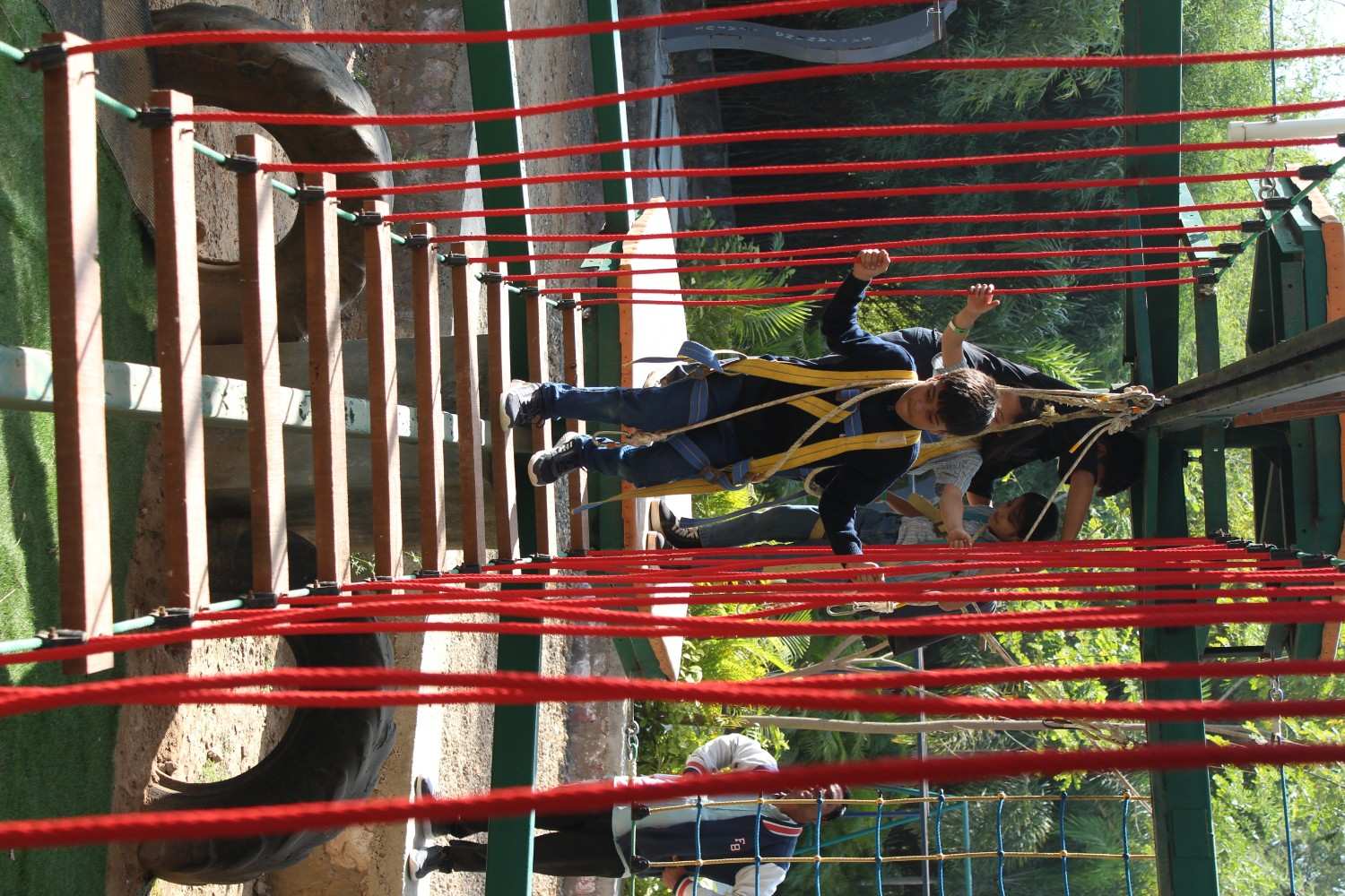 Boy carefully crossing suspension rope bridge
