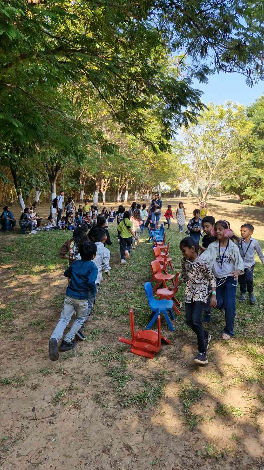 School children playing musical chairs game on a grassy field