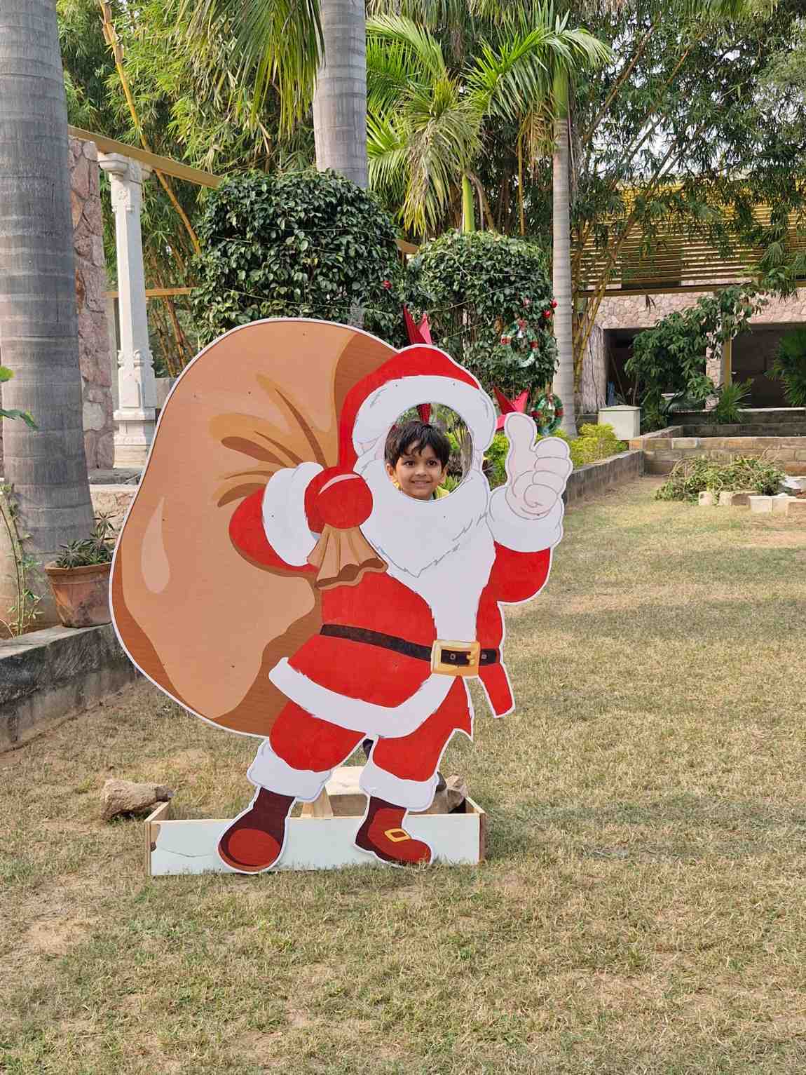 Student posing in a Santa Claus photo booth cutout outdoors