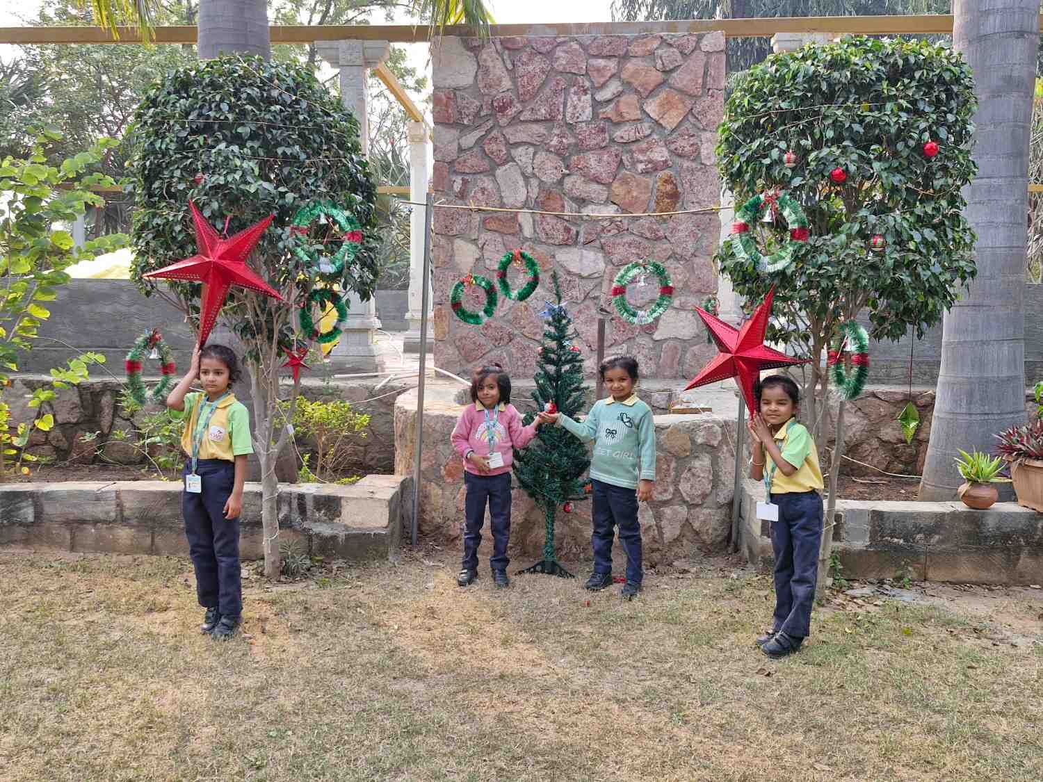 Kids posing with decorated Christmas tree during school holiday celebration
