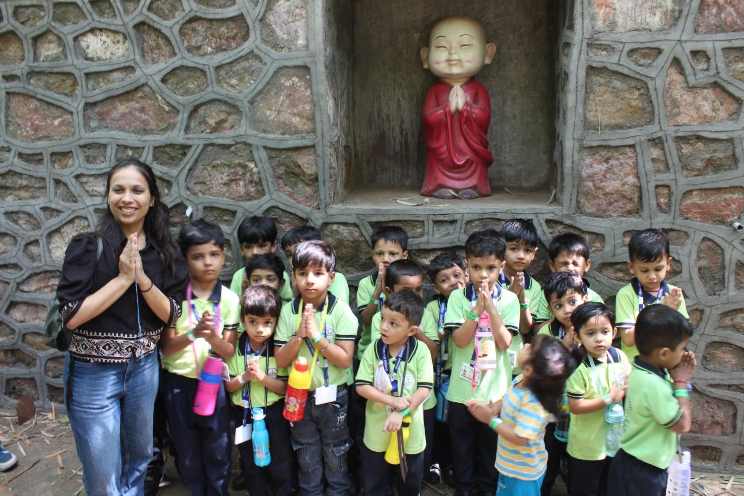 Students posing with standing Buddha statue at nature resort