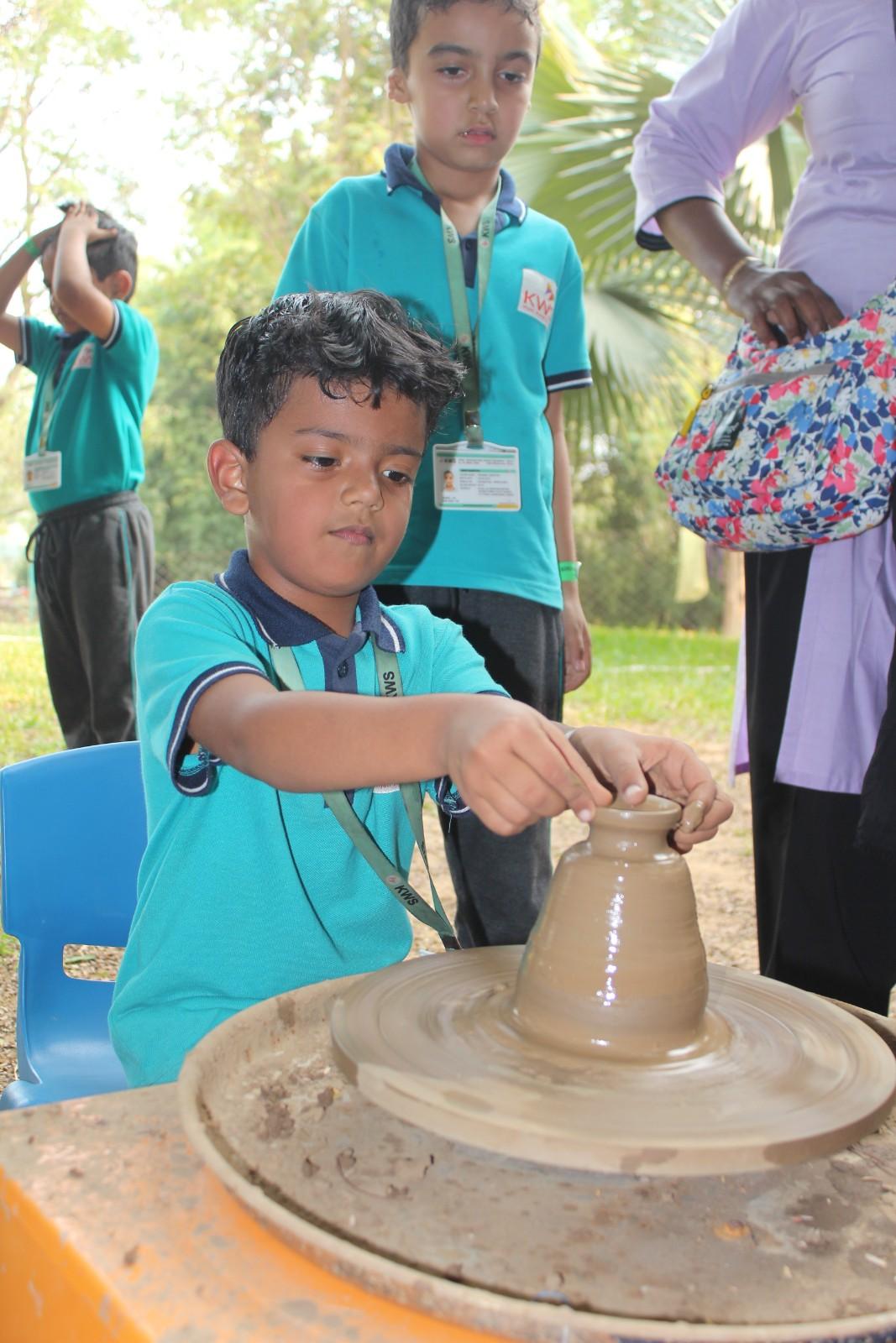 Primary student practicing traditional pottery making on a spinning wheel