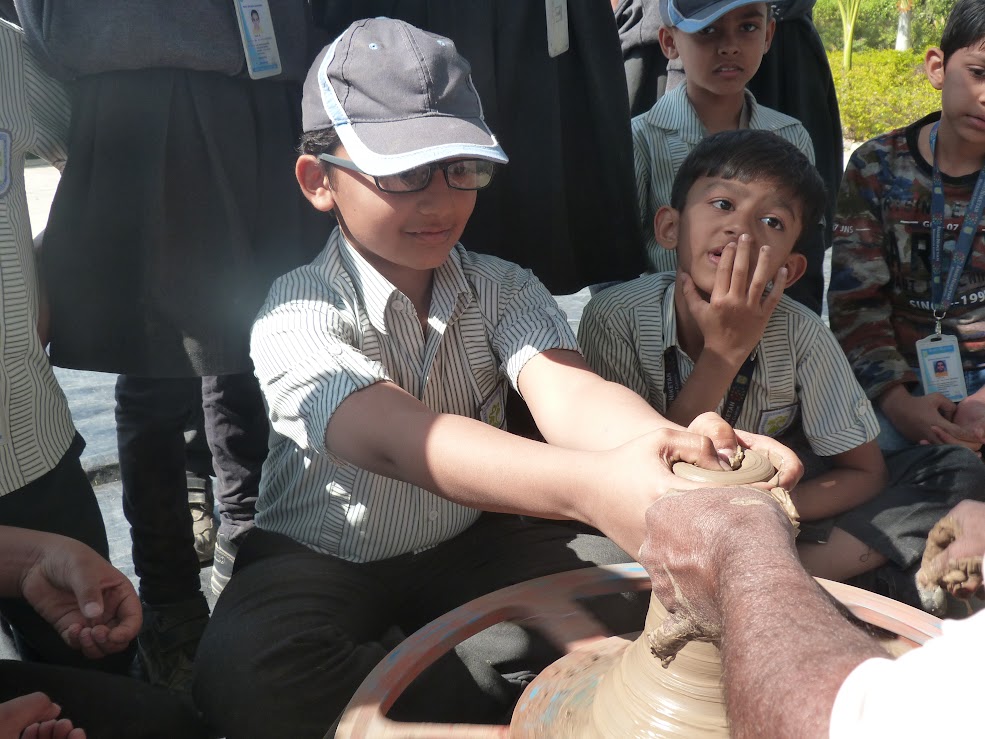 Student molding clay on pottery wheel during art workshop