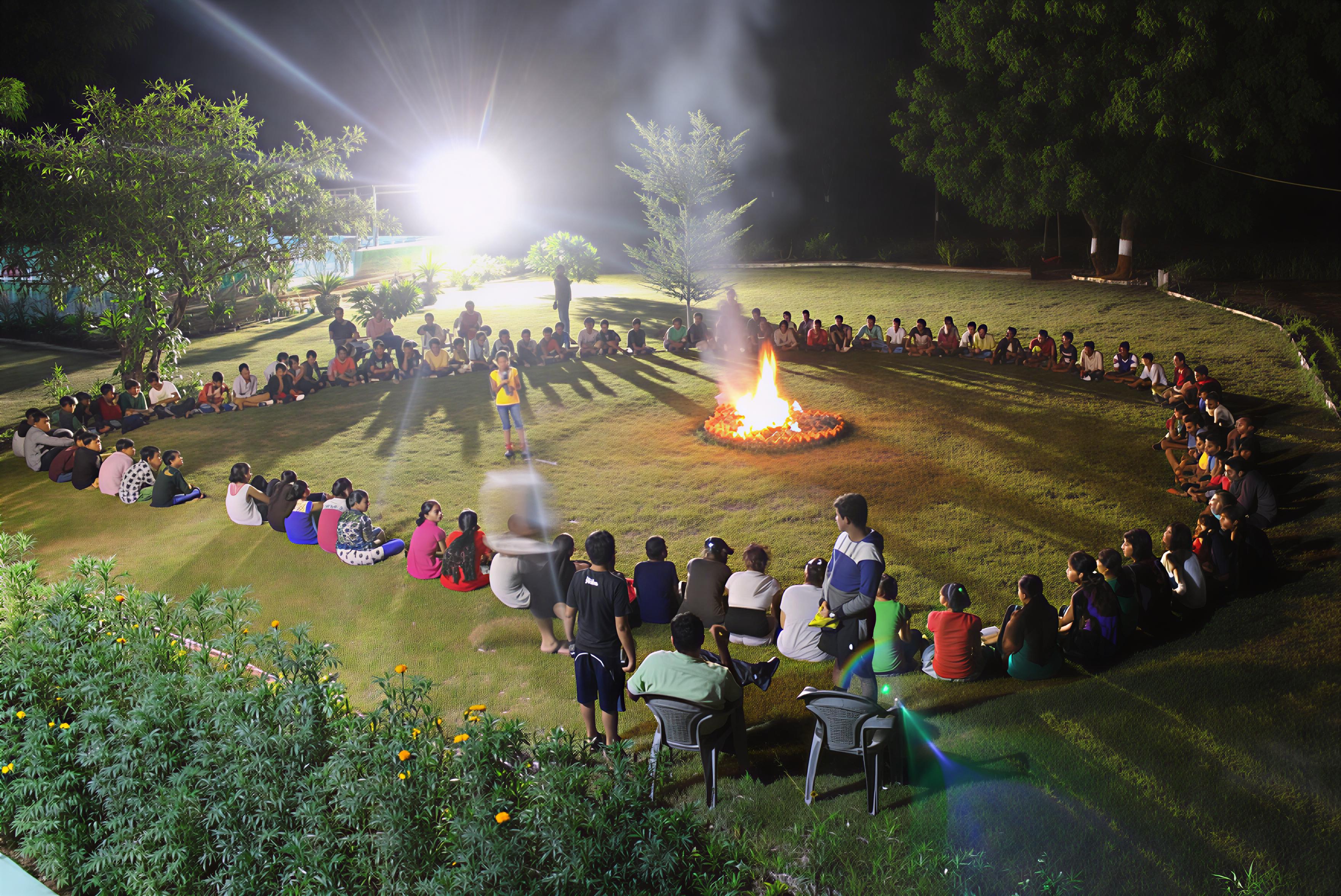 Wide shot of entire group sitting around night campfire