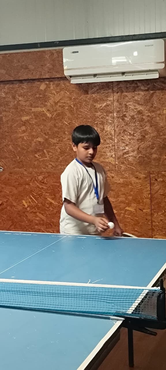 A young boy getting ready to serve a ping pong ball while playing table tennis indoors