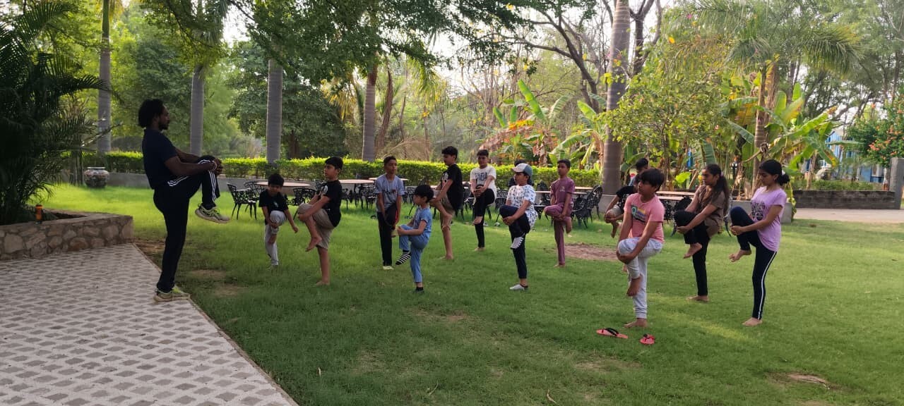 A fitness instructor teaching kids how to balance on one leg outdoors