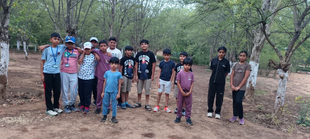 A group of kids standing together smiling in a wooded outdoor area during a Tripada School nature walk