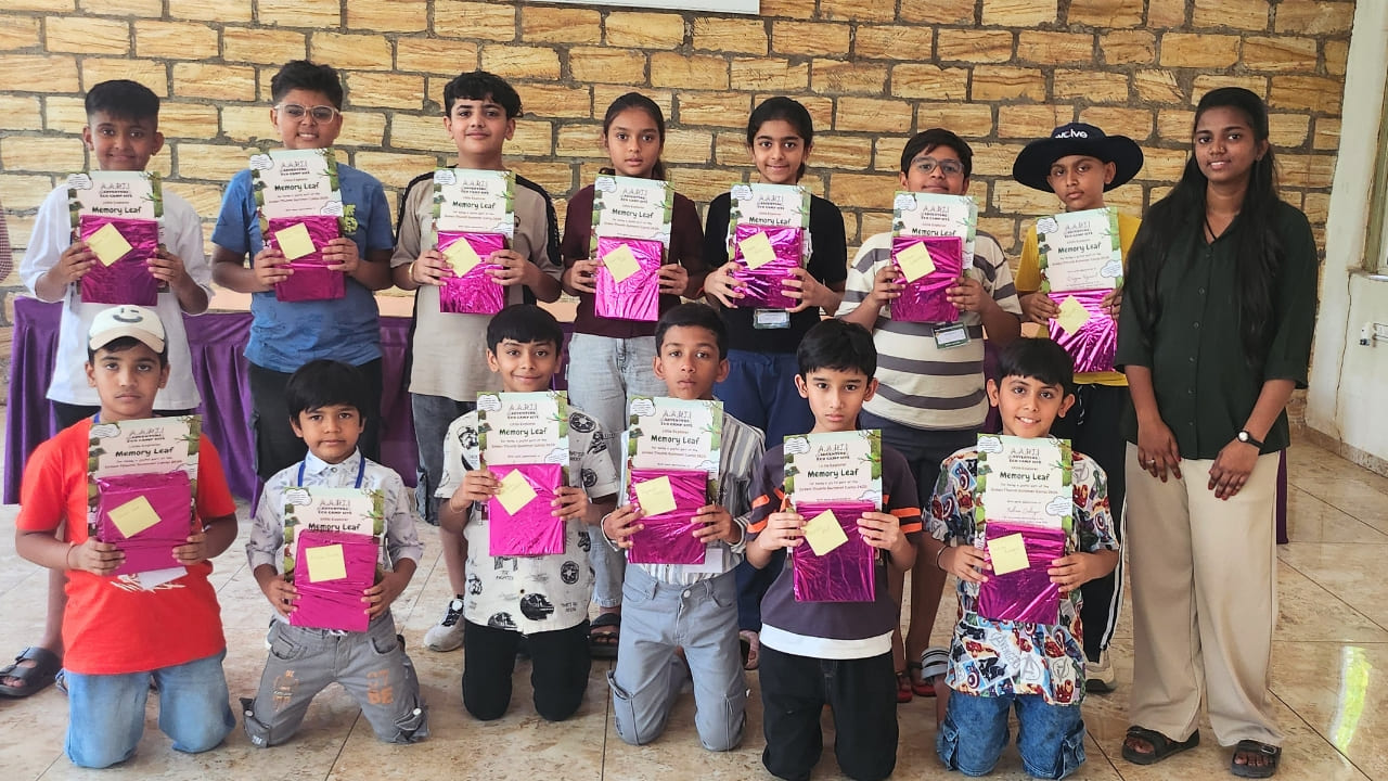 A group of children posing with pink wrapped gifts and summer camp Memory Leaf certificates