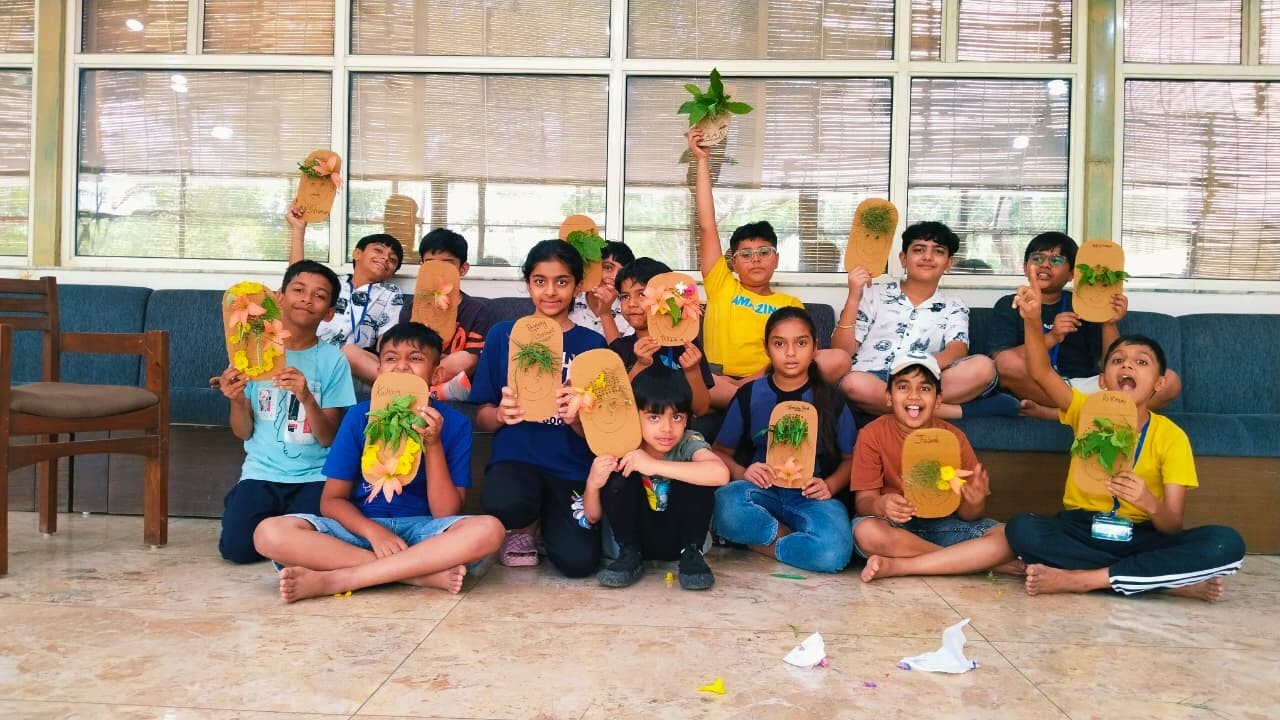 A group of happy children displaying faces they crafted using cardboard, leaves, and flowers