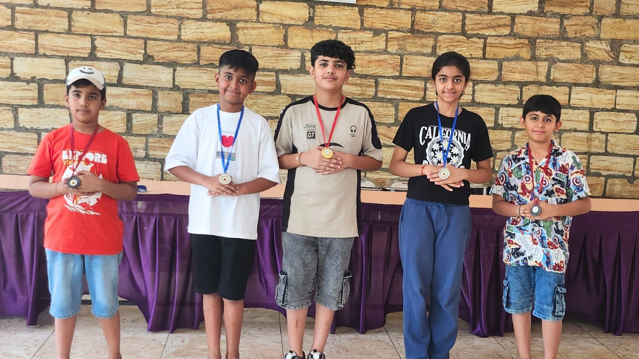 Five children standing proudly wearing medals around their necks after a summer camp activity