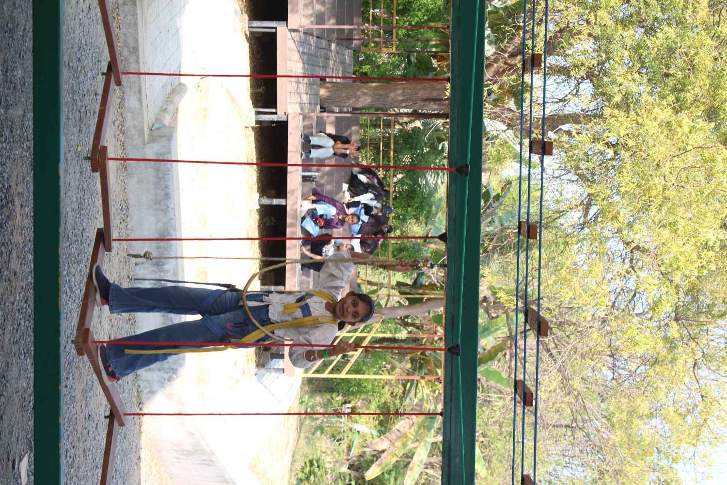 Student wearing a safety harness on a rope adventure bridge