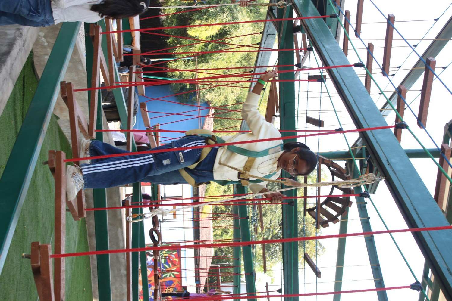 Student equipped with safety gear on a high-ropes obstacle course