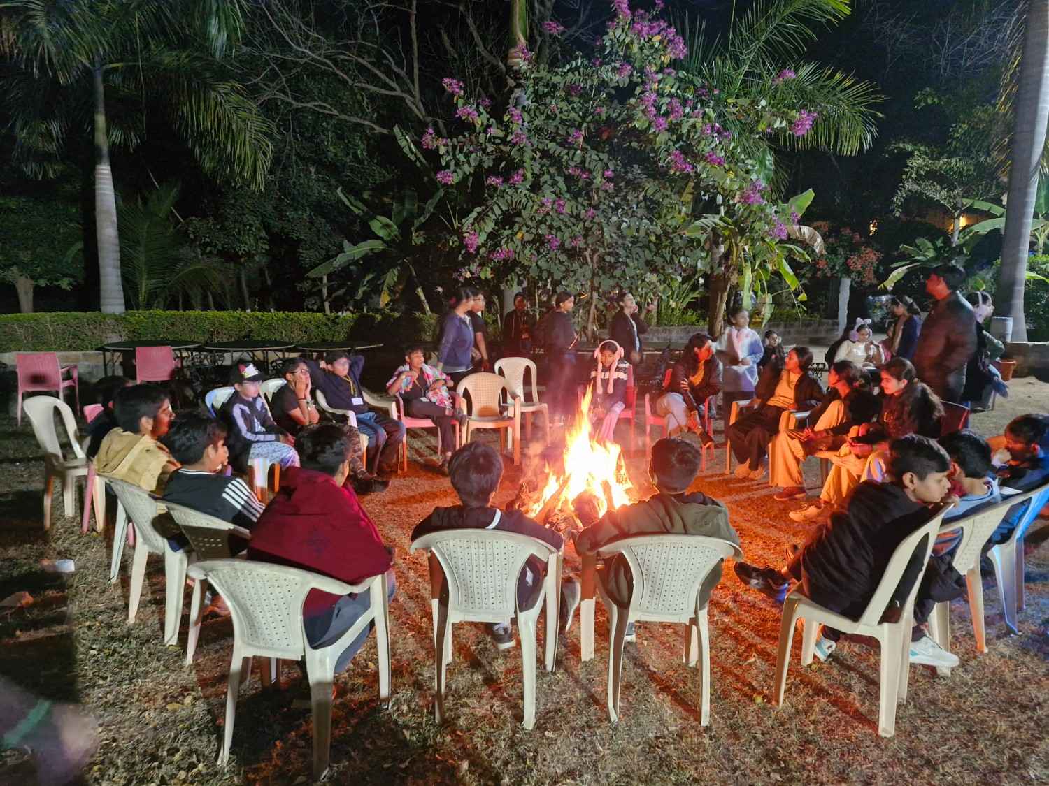 Students sitting around campfire at night