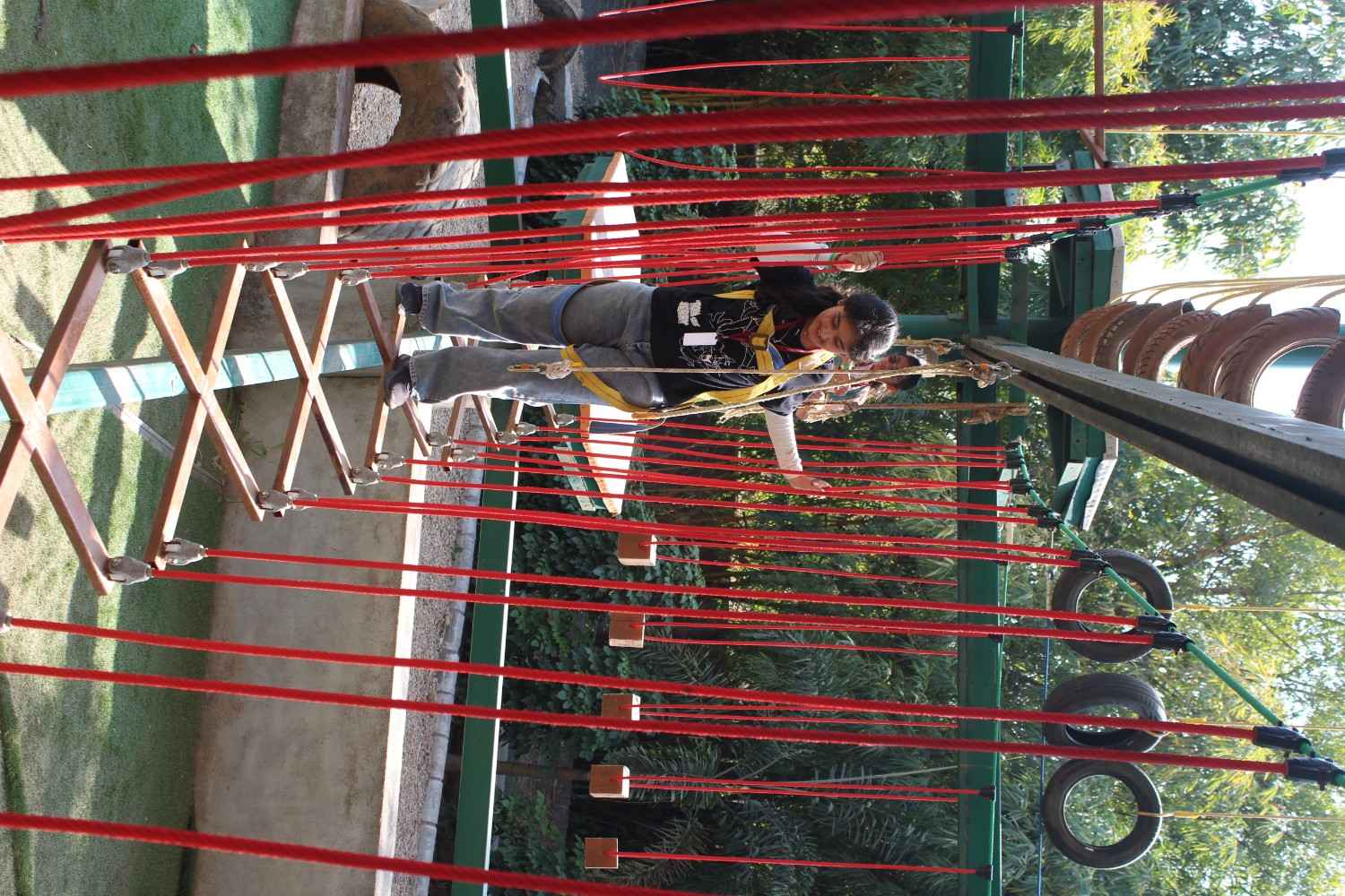 Girl student balancing on a high ropes adventure bridge