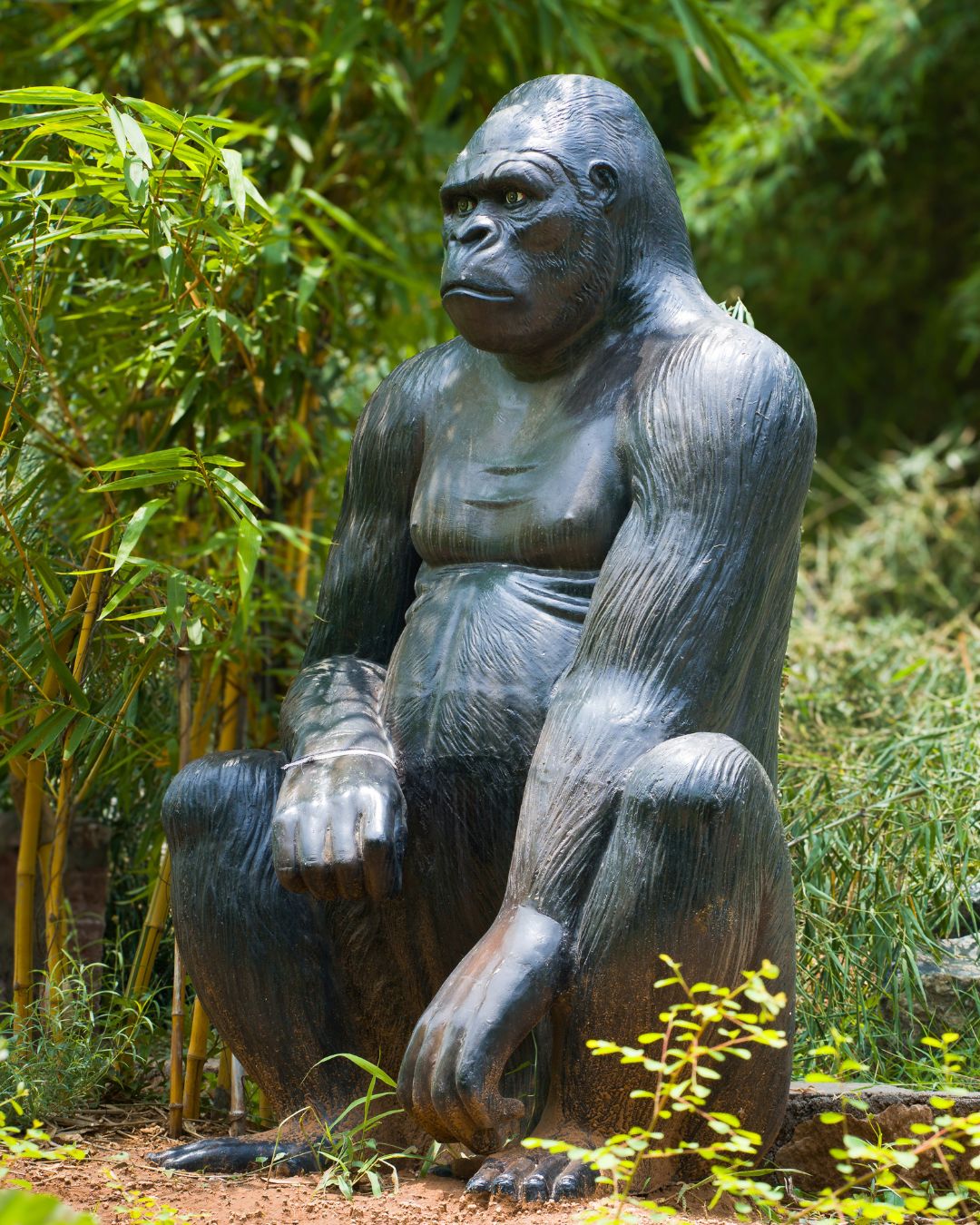 Large realistic gorilla statue sitting in green garden