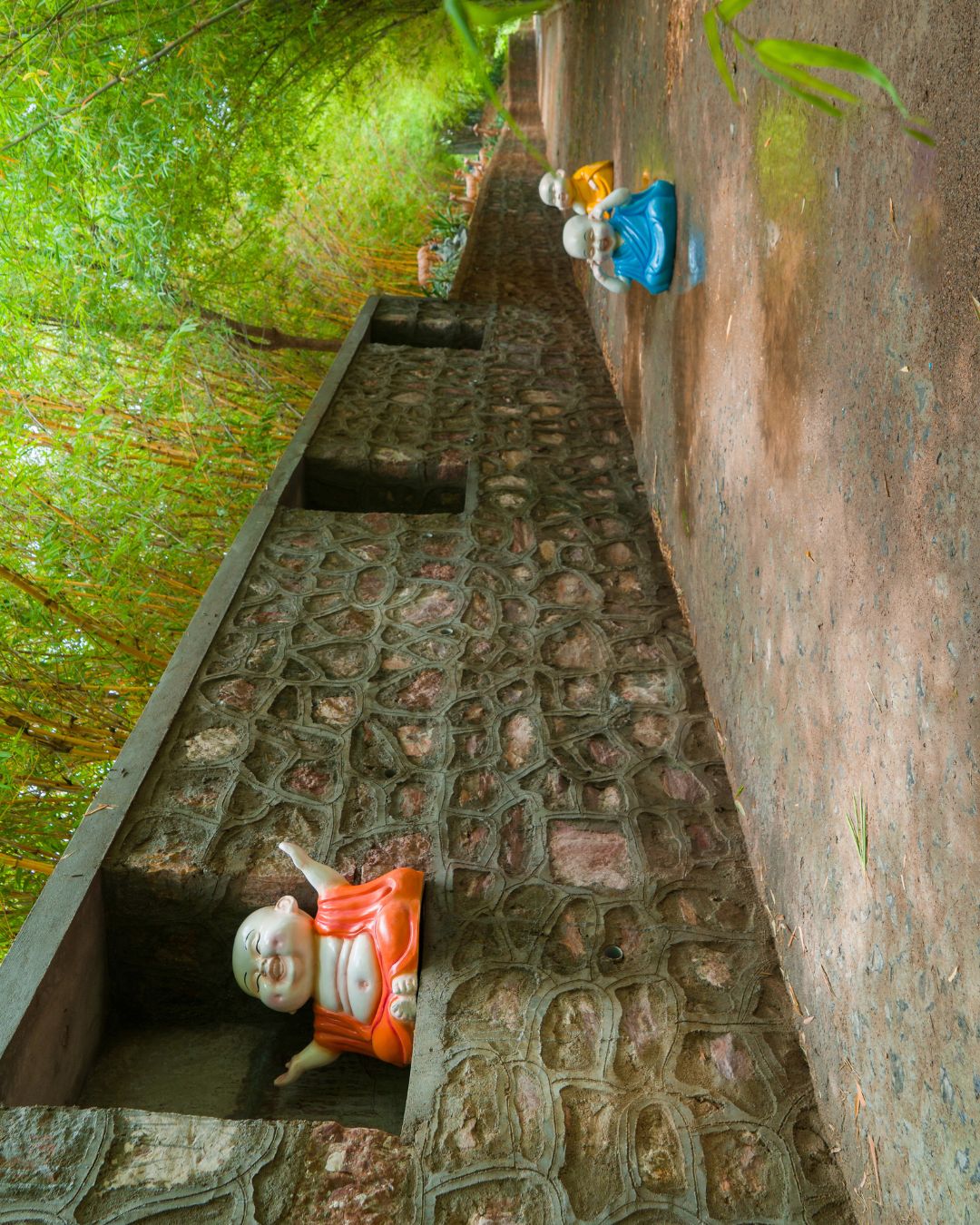 Stone wall walkway featuring various little monk statues in niches