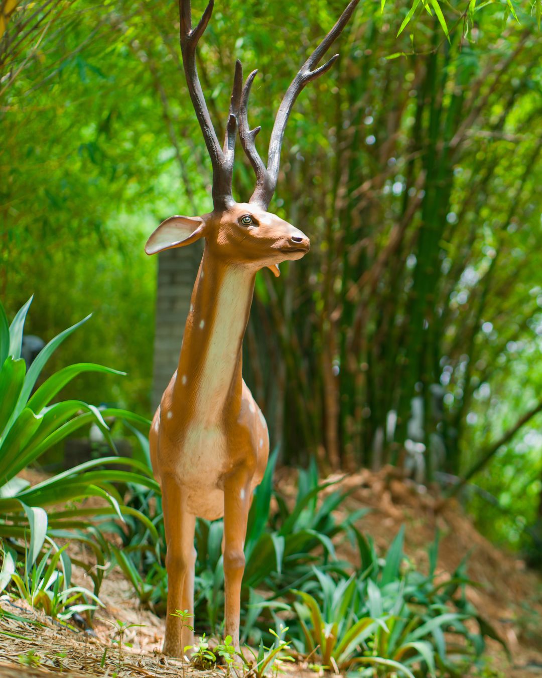 Portrait of spotted deer stag statue with antlers in forest
