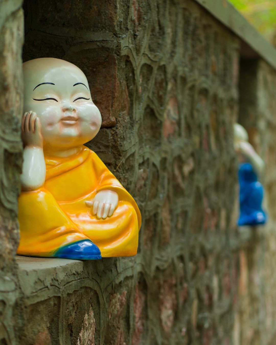 Close up profile view of thinking monk statue in yellow robe