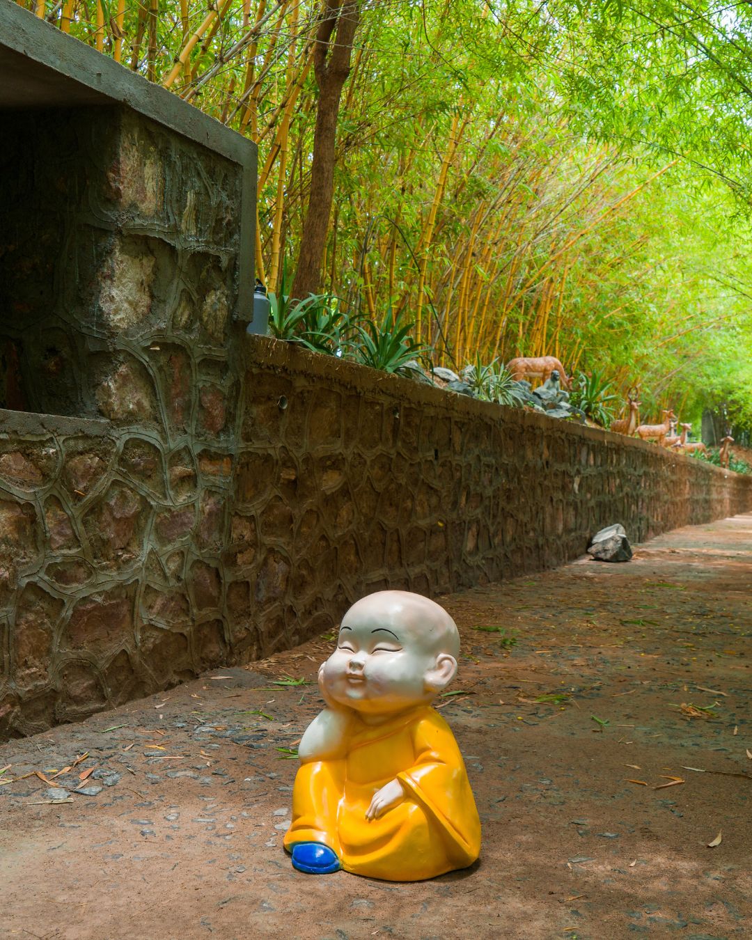 Little monk statue sitting on the ground in garden pathway